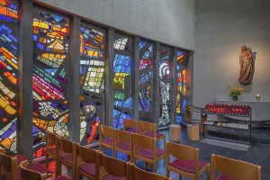 Colourful stained glass windows and a statue of the Virgin Mary with sacrificial candles