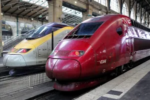 Two colourful TGV trains side by side on the platform of a railway station