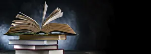 A composition with an open book lying on a stack of other books