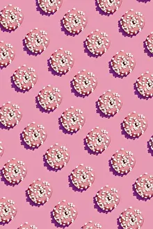 Concept food design with tasty pink glazed donut with white flakes on coral pink pastel background top view pattern
