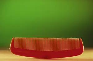 Concept, plastic comb against green background