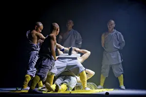 A concrete slab is being smashed on a monk while he is lying on a bed of nails
