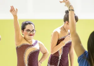 A confident gymnastic whit disability in colorful costumes perform in a bright studio