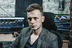 Confident man sitting in front of trading monitors in an office setting