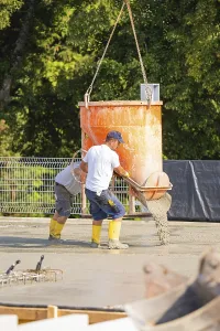 Two construction workers pouring concrete from a concrete mixer on a building site