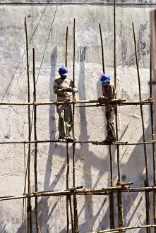 Construction workers tying bamboos with rope