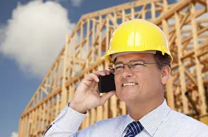 Contractor in hardhat at construction site talks on his cell phone