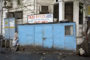 A corner of a building enclosed with a narrow structure serves as an office for taxi operators
