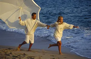 Couple on the beach, running, with parasol
