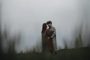 Couple embracing in a field under a cloudy sky