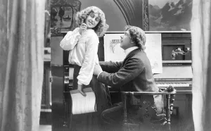 Couple, flirting, piano player holds woman's hips