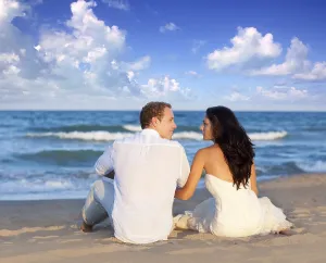 Couple in love sitting in blue beach on vacation travel
