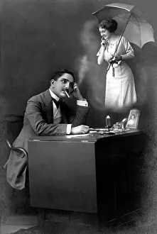 Couple, man at a desk thinking longingly of his lover