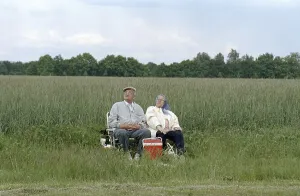 A couple of pensioners sitting on folding chairs at the edge of a field