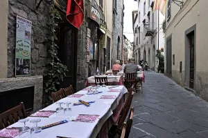 Covered tables, narrow alley with pizzeria