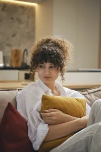 Cozy moment at home for a young woman with curls holding a pillow in a modern living space