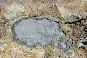 Cracked, grey crater floor with mud bubbles and geological structures