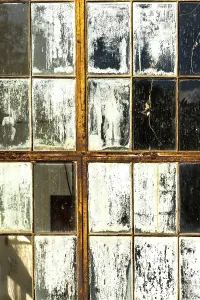 Cracked and peeling window panes reflect light and nearby objects
