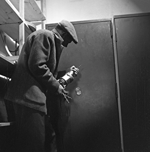 Crime in the 1960s. An arranged picture featuring a man preparing to break into a safe
