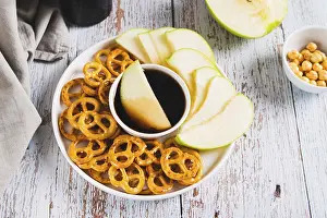 Crispy green apples and pretzels with miso caramel sauce on a plate on a table