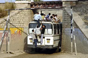 A crowded bus is passing through a narrow bridge