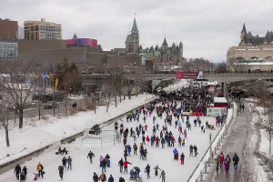 Crowded winter ice rink of the Rideau Canal in a cityscape with historical architecture