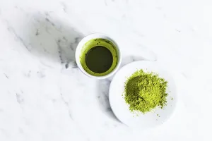 A cup of green matcha tea with matcha powder tea isolated on a light background