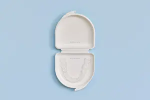 Customized transparent dental teeth bite guard clear aligners for lower jaw in white case on blue background
