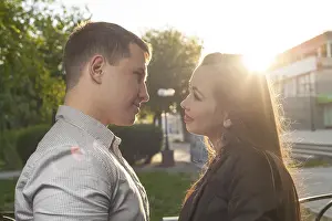 Cute Caucasian couple pose for the camera outdoors with town on background