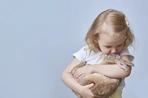 Cute girl hugs and kisses a rabbit