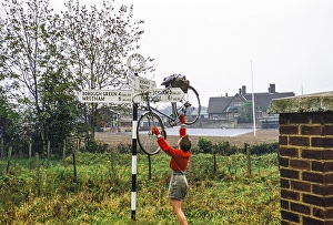 Cycling club ride in Kent, Mereworth, England, UK 1956 Woman cycling on road sign