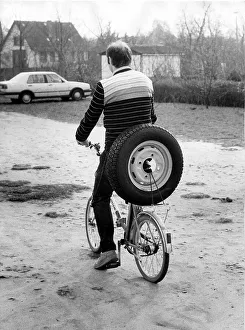 Cyclist transports car tire, approx