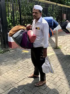 Dabbawalla with several bags on a cobbled street