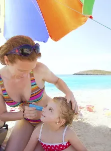 Daughter and mother in beach with sunscreen in bikini
