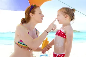 Daughter and mother in beach with sunscreen in bikini