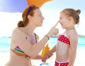 Daughter and mother in beach with sunscreen in bikini
