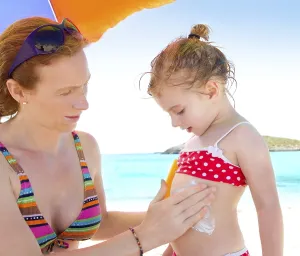 Daughter and mother in beach with sunscreen in bikini