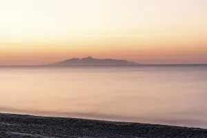 Dawn at sunrise, view from the lava beach near Kamari to the island of Anafi
