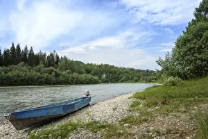 Daytime landscape with a mountain river among coniferous forest with a motorboat on a rocky shore