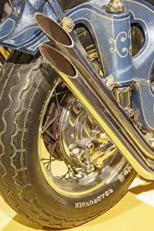 Decorated blue motorbike exhaust with tyres on a yellow base