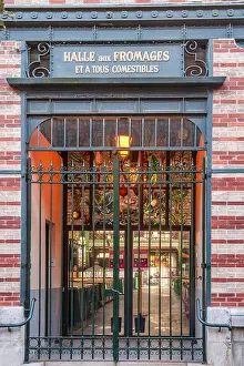 Decorated brick facade with clock and wrought-iron entrance to the cheese section of the market hall