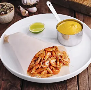Delicious plate of cooked shrimp served with golden sauce and lime