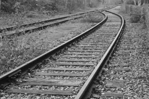 Deserted railway track disappearing into the woods in a black and white image of abandonment and decay