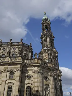 Detailed baroque church tower in front of blue sky and clouds