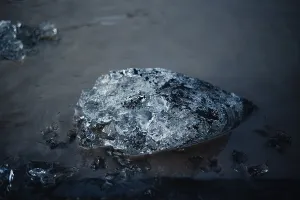 Detailed shot of a dark, wet ice chunk resting on the water