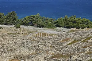 Detailed view of the ruins of an ancient site in front of a blue sea and green trees