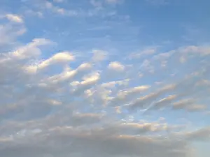 Diagonally arranged stratocumulus clouds are illuminated by warm sunlight at dusk