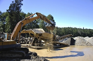 Digger feeding gravel into small gold screen