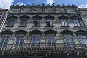 Dilapidated residential building with balcony and sculptures on the roof ledge