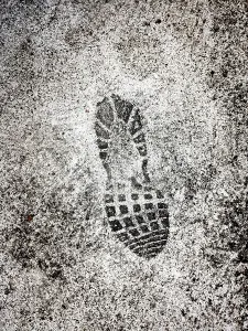 A distinct shoe print is marked on a wet surface